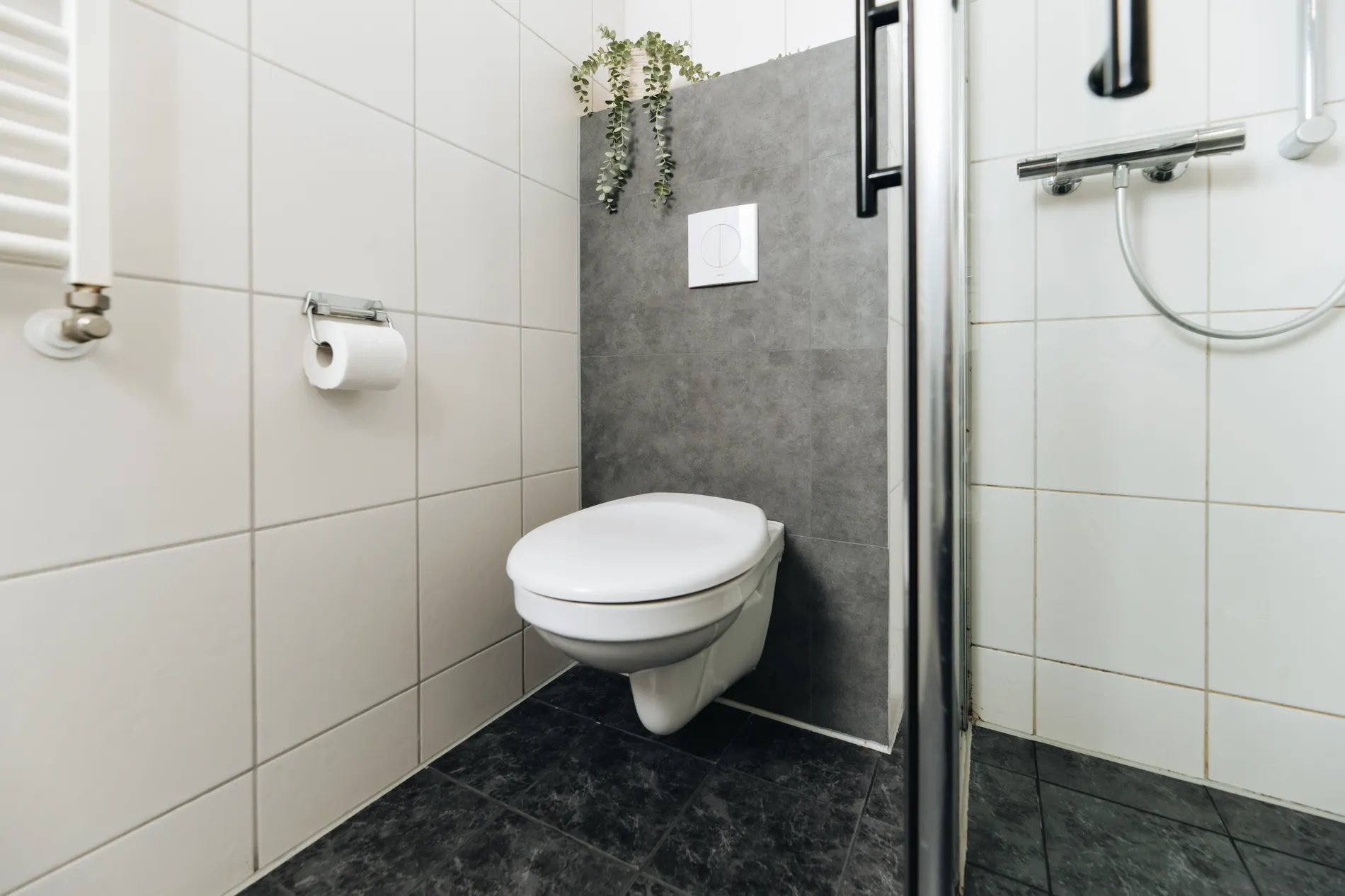 Detail van het moderne, hygiënische toilet in de hotelkamer van Resort Land & Zee met stijlvolle grijze wandafwerking.